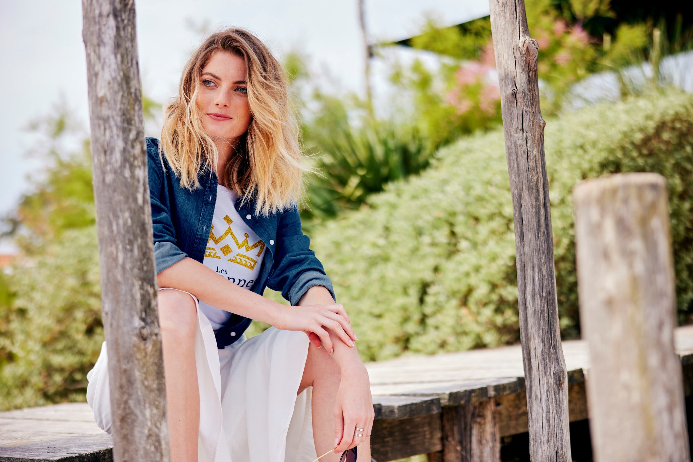 Jeune femme assise sur un ponton et portant un sweat shirt de la marque régionale Les Couronnes.