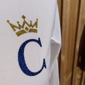 Zoom sur le logo bleu royal et or d'une chemise de la marque de prêt à porter Les Couronnes.