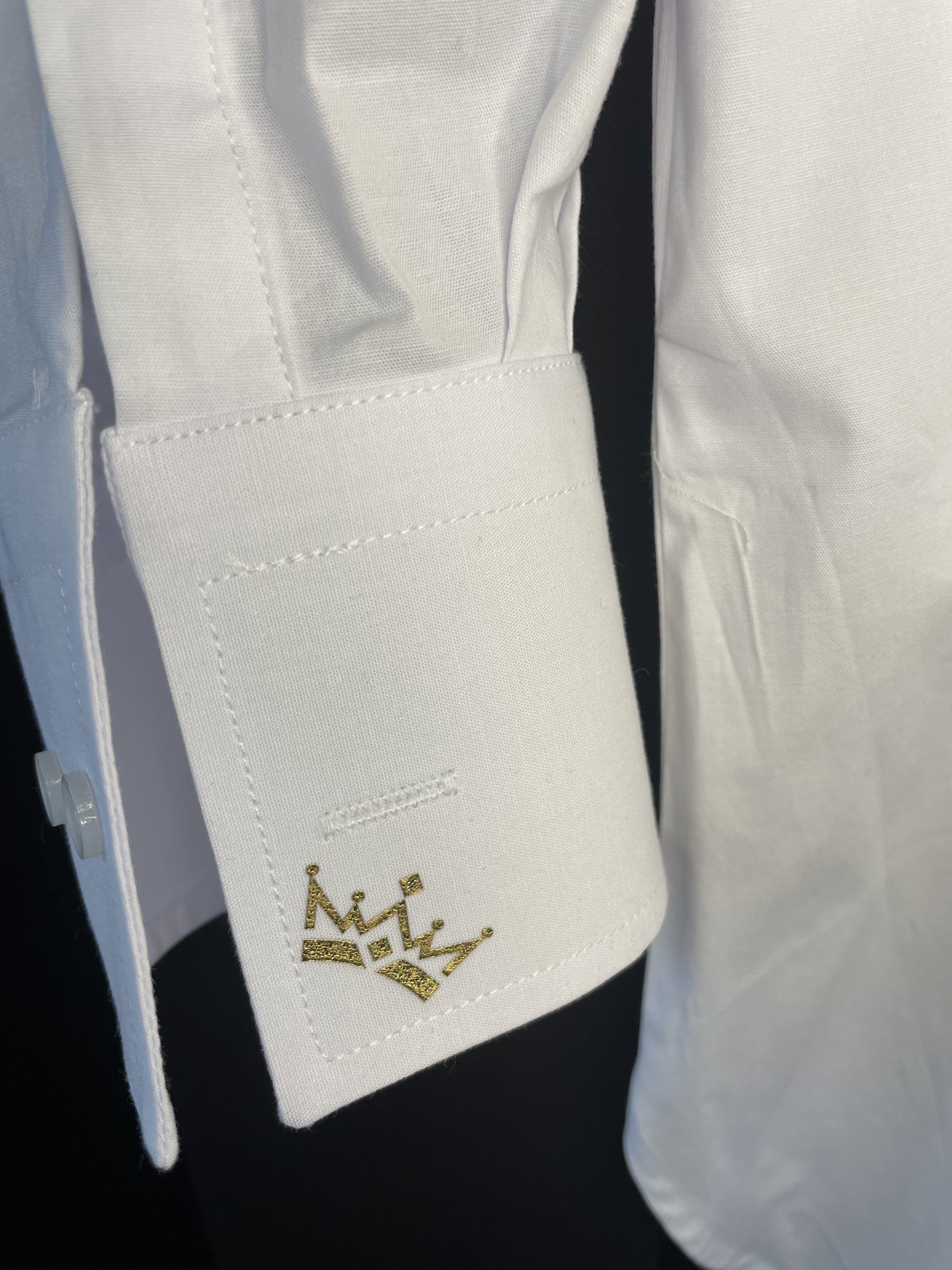 ZOOM SUR LE POIGNET D’UNE CHEMISE AVEC DES COURONNES